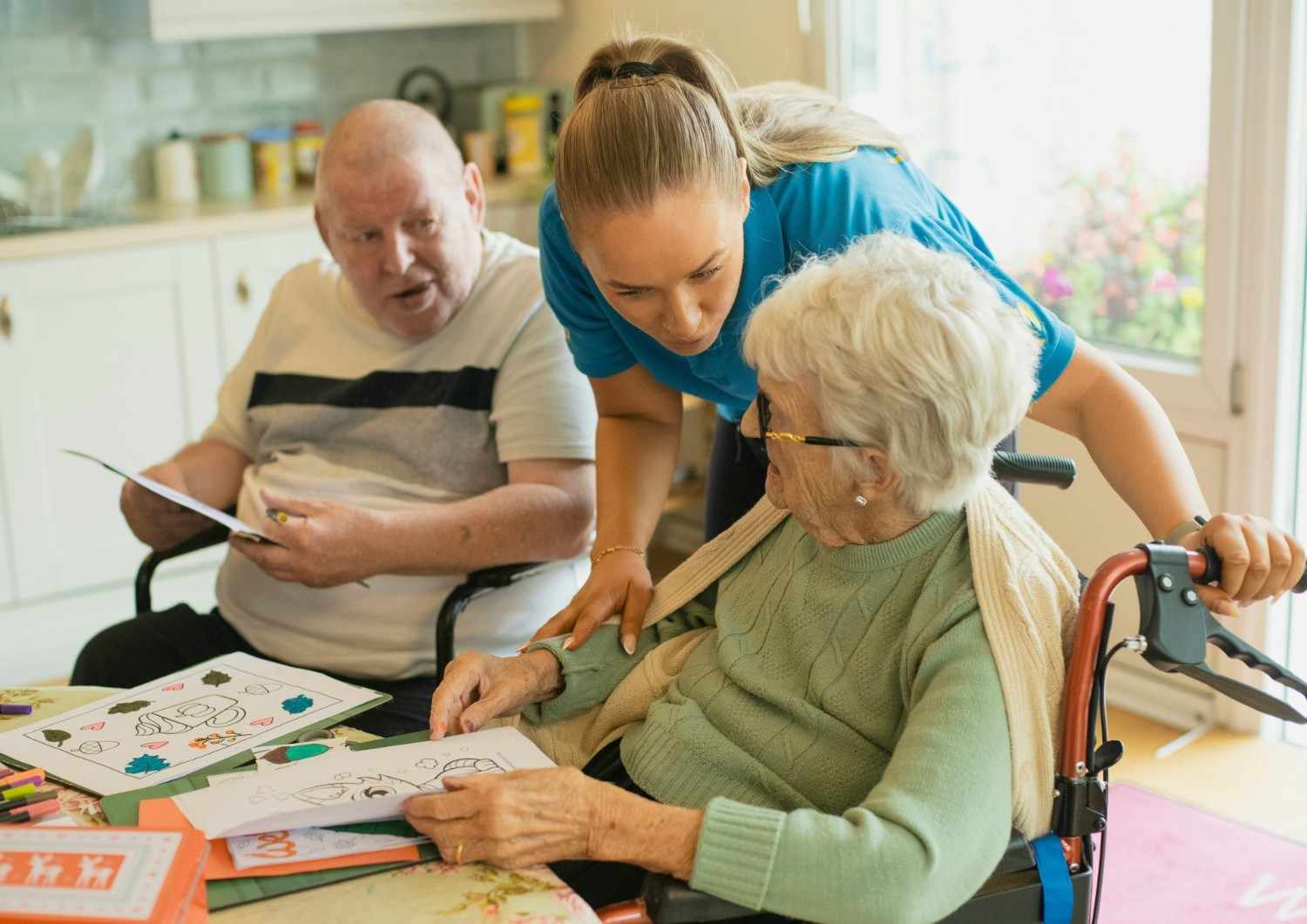 Caregiver assisting elderly couple with coloring